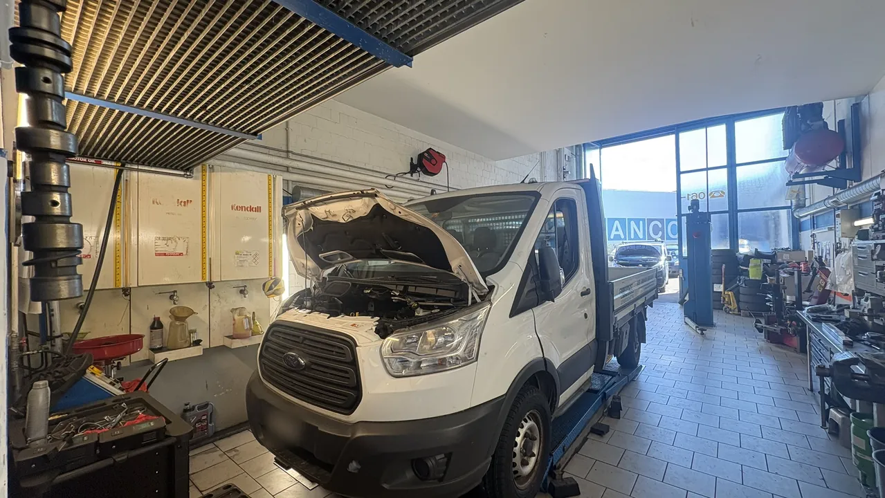 Werkstatt der Rotterdam Garage mit Hebebühne, Werkzeugwand und Arbeitsbereich.